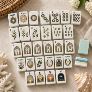 K&ouml;nnte beinhalten: Eine Sammlung wei&szlig;er rechteckiger Mahjong-Spielsteine mit verschiedenen Illustrationen, darunter Zahlen, florale Motive, Buntglasfenster-Designs und Himmelsrichtungen. Die Steine zeigen Texte wie JOKER, SOAP, FLOWER, E, S, W und N.