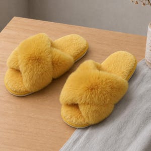 May include: A pair of bright yellow slippers featuring a plush, fuzzy texture and a crisscross strap design across the top. The slippers have an open-toe construction and a flat, solid-colored sole, providing a soft and uniform appearance.