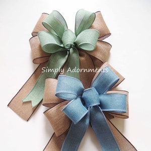 May include: Two burlap ribbon bows with a green and blue ribbon center. The bows are tied together with a brown ribbon.