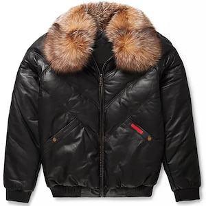 Könnte beinhalten: Eine schwarze Leder-Bomberjacke mit einem großen, flauschigen braunen Pelzkragen, einem Frontreißverschluss und einem gesteppten Chevron-Muster. Die Jacke verfügt über zwei Seitentaschen mit Druckknöpfen und ein kleines rotes Akzentdetail.