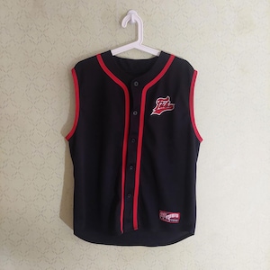 May include: A black sleeveless baseball jersey featuring red trim along the collar, armholes, and front button placket. The garment displays a red and white Fubu logo on the left chest and a rectangular Fubu patch on the lower left front hem.