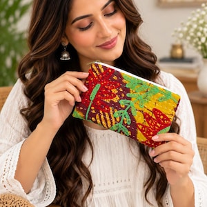 May include: A rectangular zippered pouch featuring a vibrant patchwork design with deep maroon, mustard yellow, and bright green fabric panels. The surface is decorated with intricate, contrasting green hand-stitched embroidery patterns.