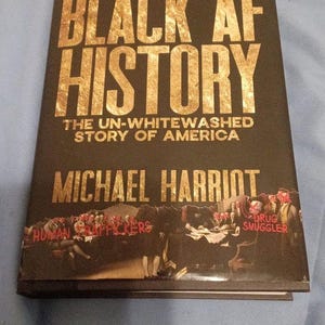 May include: A hardcover book titled Black AF History: The Un-Whitewashed Story of America by Michael Harriot. The black cover features gold lettering and a historical illustration with red text overlays including Human Traffickers and Drug Smuggler.