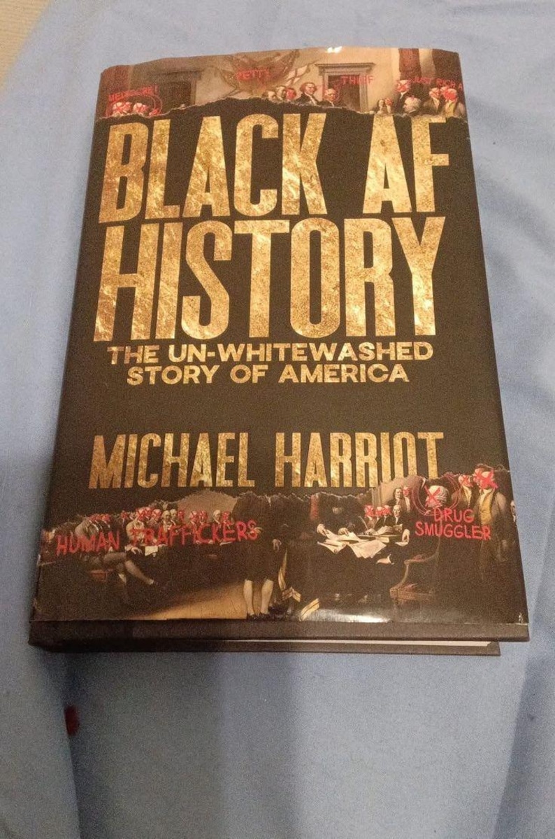 May include: A hardcover book titled Black AF History: The Un-Whitewashed Story of America by Michael Harriot. The black cover features gold lettering and a historical illustration with red text overlays including Human Traffickers and Drug Smuggler.