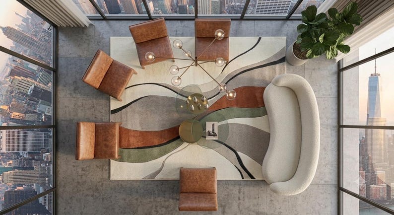 May include: A top-down view of a living room set featuring a curved cream sofa, four brown leather armchairs, and a round glass coffee table. A large area rug displays abstract wavy bands of cream, rust orange, olive green, and charcoal gray.