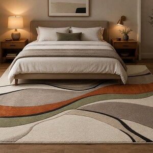 May include: A rectangular area rug featuring a large-scale abstract pattern of flowing, organic shapes in shades of cream, beige, sage green, burnt orange, and charcoal gray. The rug has a low-pile texture and is positioned under a bed frame.