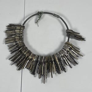 Könnte beinhalten: Ein großer kreisförmiger Metallring, der eine dichte Ansammlung zahlreicher silber- und messingfarbener Schlüssel unterschiedlicher Form und Größe hält. Die Schlüssel sind entlang des dunkelgrauen Metallrings angeordnet, der einen Schraubverschluss hat.