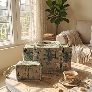 Puede incluir: Una bolsa de viaje rectangular y un neceser a juego, ambos de tela beige con un estampado de selva en verde y marr&oacute;n con animales y palmeras, rematados con ribetes a rayas verdes y blancas en los bordes y las asas.