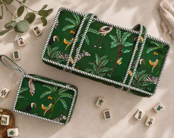 Puede incluir: Un estuche de almacenamiento rectangular verde y una bolsa rectangular más pequeña a juego, ambos con un estampado de selva tropical con pájaros y cebras, acabados con ribetes a rayas blancas y negras y asas de tela a juego.