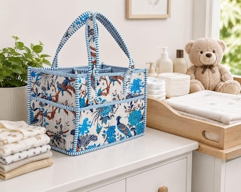 May include: A rectangular fabric storage caddy featuring a white base with a blue and brown botanical print of birds and flowers. The caddy has two upright handles and blue and white striped trim along the edges, with multiple exterior pockets.