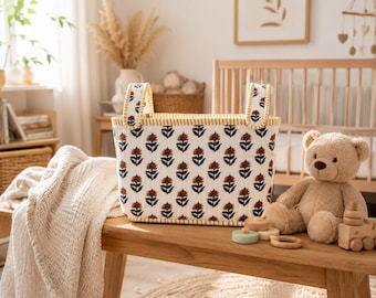 May include: A rectangular fabric storage basket featuring a white base with a repeating floral pattern in dark blue and rust orange. The basket has two upright handles, a quilted texture, and a yellow stitched trim along the top edge and handles.