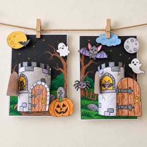 Peut inclure: Deux créations en papier rectangulaires présentant des tours de château en relief 3D sur un fond de ciel nocturne noir. Les scènes incluent des éléments dessinés à la main comme une lune jaune, une lune grise, des fantômes, des chauves-souris, une araignée, une citrouille et un chat noir dans une fenêtre.