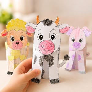 May include: Three paper tube animal crafts featuring a yellow sheep, a black and white cow, and a pink pig. Each figure is hand-coloured with crayons, showing distinct facial features, ears, and limbs attached to cylindrical cardboard bases.