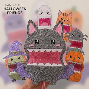 Può includere: Una collezione di marionette di carta fatte a mano di amici di Halloween con un pipistrello nero centrale con ali viola, una strega verde, un fantasma bianco, un gatto arancione, un ragno nero e una zucca arancione, tutti con la bocca spalancata.