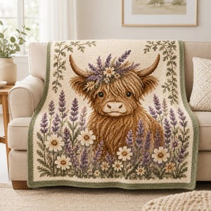 May include: A rectangular crochet blanket featuring a central brown Highland cow with a floral crown of purple lavender and white daisies. The background is cream-coloured with green foliage borders and a field of lavender and daisies at the bottom.