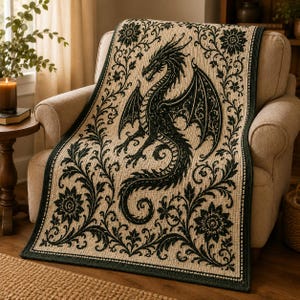 Può includere: Una coperta rettangolare tessuta con un'illustrazione di un drago verde scuro centrata su uno sfondo color crema. Il design è incorniciato da un bordo verde scuro con intricati motivi floreali e di viticci che decorano tutto il tessuto.