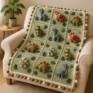 May include: A sage green crochet blanket featuring three-dimensional dinosaur appliques and patterned eggs in individual squares. The blanket is bordered with a cream-coloured trim decorated with small, alternating green and orange pom-poms.
