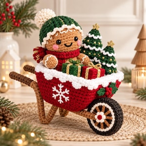 May include: A crocheted gingerbread person wearing a green hat and red scarf, sitting in a red wheelbarrow with a white snowflake design. The wheelbarrow contains two small crocheted Christmas trees and two wrapped gift boxes with gold ribbons.