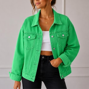 May include: A bright green denim jacket featuring a classic collar, long sleeves with buttoned cuffs, and two chest pockets with button-down flaps. The jacket has a front button closure and is worn over a white crop top and black jeans.