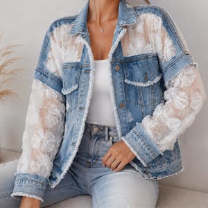 Puede incluir: Una chaqueta de mezclilla azul con mangas largas y paneles superiores de encaje blanco transparente con un patrón floral de margaritas. La chaqueta incluye un cuello clásico, cierres de botones metálicos, dos bolsillos en el pecho y bordes deshilachados.