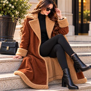 May include: A long, rust-colored coat featuring a tan sherpa-style lining, wide lapels, and folded cuffs. The coat is worn over a black turtleneck sweater, black leggings, and black leather block-heel ankle boots, accompanied by a black handbag.
