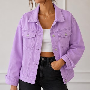May include: A light purple denim jacket featuring a classic collar, long sleeves with buttoned cuffs, and two chest pockets with button-down flaps. The jacket has a front button closure with metallic buttons and is worn over a white crop top.
