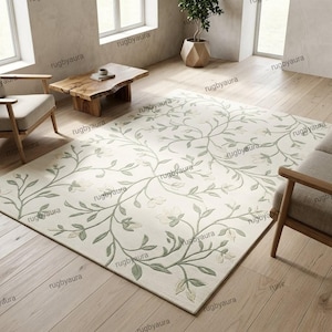 May include: A rectangular area rug featuring a cream-colored background with a repeating pattern of sage green vines, leaves, and small flowers. The design is symmetrical, spreading across the surface of the rug in a flowing, organic arrangement.