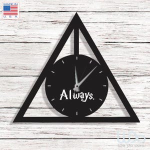 Puede incluir: Un reloj de pared negro con un marco triangular y una línea vertical en el centro. La esfera circular es negra con marcas blancas, manecillas plateadas y la palabra Always. impresa en texto blanco en la parte inferior central.