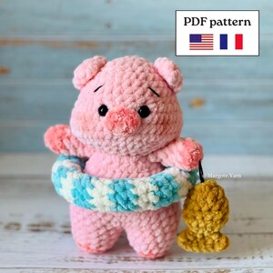 Peut inclure: Une peluche cochon crochetée rose avec une finition en fil texturé, des yeux en perles noires et un museau. Le cochon porte une bouée de natation crochetée à motifs bleus et blancs et tient un petit poisson crocheté jaune. Texte PDF pattern.