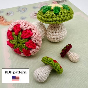 Peut inclure: Trois champignons au crochet avec des tiges couleur crème et des chapeaux texturés en vert, rose et rouge. Le plus grand chapeau présente un motif floral vert et rose, tandis que les autres ont des sommets unis. Texte PDF pattern inclus.