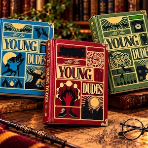 以下が含まれることがあります： 青、赤、緑のイラスト入り表紙を持つ「All The Young Dudes」というタイトルのハードカバー本3冊。各本には金色のコーナープロテクターが付いており、動物や機械的な要素を含むグラフィックアイコンのグリッドが描かれています。