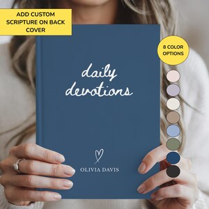 May include: A dark blue hardcover journal with the white text daily devotions and a heart icon above the name Olivia Davis. A yellow box states add custom scripture on back cover and a yellow circle indicates 8 color options with color swatches.