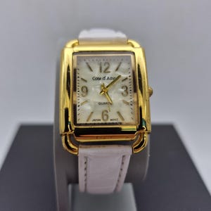 Vintage-inspired Cote D'Azur women's  quartz  watch,features a classic rectangular tank gold-tone case, white strap mother of pearl dial