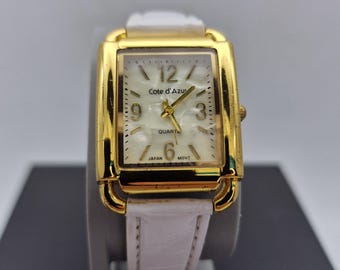 Vintage-inspired Cote D'Azur women's  quartz  watch,features a classic rectangular tank gold-tone case, white strap mother of pearl dial