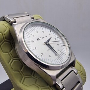 A authentic pre-owned Ben Sherman BS095 Men's Quartz Watch. Featuring a unique brushed silver analogue display, this timepiece stands out with its striking blue-accented numerical markers and precise 3-hand design. The durable stainless steel case is paired with a matching silver-toned metal link bracelet,
