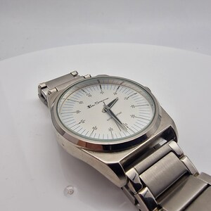 A authentic pre-owned Ben Sherman BS095 Men's Quartz Watch. Featuring a unique brushed silver analogue display, this timepiece stands out with its striking blue-accented numerical markers and precise 3-hand design. The durable stainless steel case is paired with a matching silver-toned metal link bracelet,
