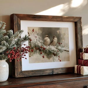 May include: A framed print featuring two small birds perched on a snow-covered pine branch with red berries. The artwork is enclosed in a dark, rustic wooden frame with a white mat, capturing a winter scene with soft, muted tones and textures.