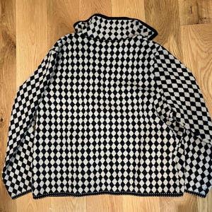 K&ouml;nnte beinhalten: Ein lang&auml;rmeliger Pullover mit einem sich wiederholenden schwarz-wei&szlig;en Rautenmuster auf dem gesamten Kleidungsst&uuml;ck. Der Pullover verf&uuml;gt &uuml;ber einen Umlegekragen sowie schwarze S&auml;ume an Kragen, &Auml;rmelb&uuml;ndchen und am unteren Saum.