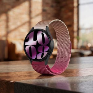 May include: A smartwatch with a black circular case and a metallic mesh band that features a gradient color transition from light rose gold at the top to deep magenta at the bottom. The watch face displays the large white numbers 10 and 08.
