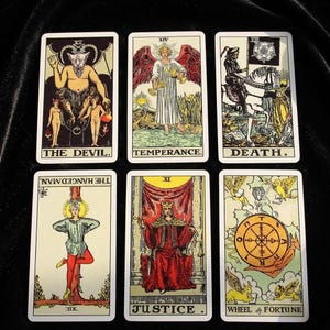 Puede incluir: Seis cartas de tarot dispuestas en dos filas. Fila superior: El Diablo, Templanza y La Muerte. Fila inferior: El Colgado, Justicia y La Rueda de la Fortuna. Cada carta presenta ilustraciones detalladas con etiquetas de texto en la parte inferior.