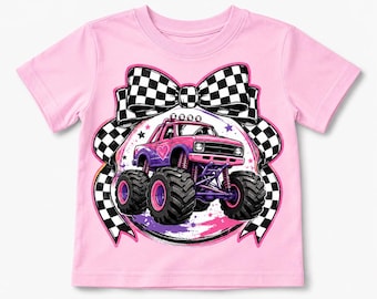 Puede incluir: Una camiseta de manga corta de color rosa claro con un estampado gráfico de un camión monstruo rosa con un corazón en el lateral, situado delante de un gran lazo a cuadros blancos y negros. El diseño incluye pequeñas estrellas moradas y rosas.