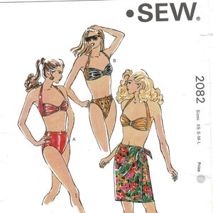 May include: A vintage sewing pattern for swimwear, featuring three different bikini designs. The illustration shows a red bikini, a black and gold bikini, and an orange bikini with a floral wrap skirt. The pattern is labeled "SEW" and includes sizes XS-S-M-L.