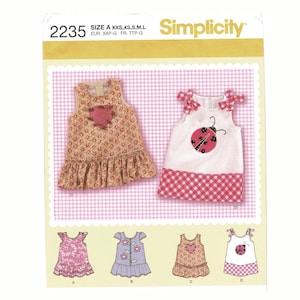 May include: Simplicity sewing pattern 2235 featuring several baby dress designs. The dresses include floral prints, ladybug and heart appliqués, and ruffled hems. The pattern includes sizes XXS to L.