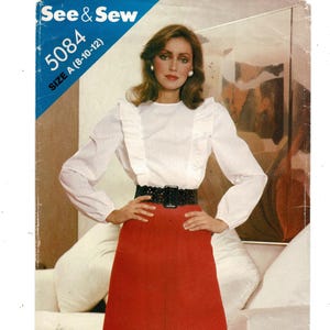 May include: A vintage sewing pattern cover featuring a woman in a white blouse with ruffled trim, a red skirt, and a black belt. The pattern is labeled "See & Sew" with the number 5084 and size A (8-10-12).