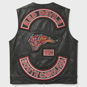 May include: A black leather vest featuring embroidered patches on the back. The top patch reads RED DEVILS in red and white. A central patch depicts a red horned devil head with flames. A small patch reads MC. The bottom patch reads SOUTH CAROLINA.