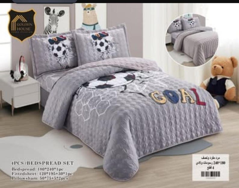 May include: A four-piece bedspread set in grey featuring a soccer ball pattern and the word GOAL in large letters. The set includes a quilted bedspread, a fitted sheet, and two pillow shams, all decorated with soccer-themed graphics and motifs.