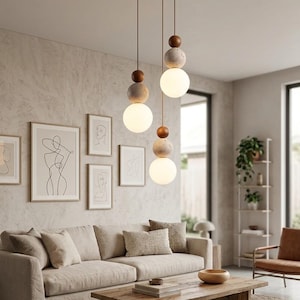 Peut inclure: Un luminaire suspendu composé de trois cordons verticaux fixés au plafond. Chaque cordon est orné d'une sphère en bois brun foncé, d'une sphère en pierre grise texturée et d'une ampoule sphérique en verre blanc lisse à la base.
