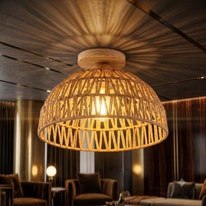 Op de afbeelding: Een plafondlamp met een koepelvormige kap gemaakt van gevlochten beige touw in een geometrisch patroon. De armatuur bevat een ronde basis van lichtgekleurd hout die aan het plafond is bevestigd en een enkele gloeiende lamp bevat.
