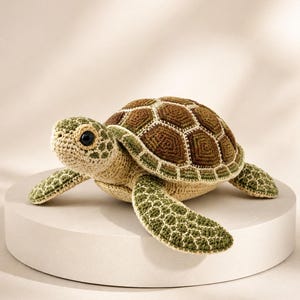 Pu&ograve; includere: Un peluche a forma di tartaruga marina realizzato all'uncinetto, con un guscio testurizzato caratterizzato da motivi geometrici marroni e verdi. La testa e le pinne sono in filato beige chiaro con accenti verdi e un occhio nero.