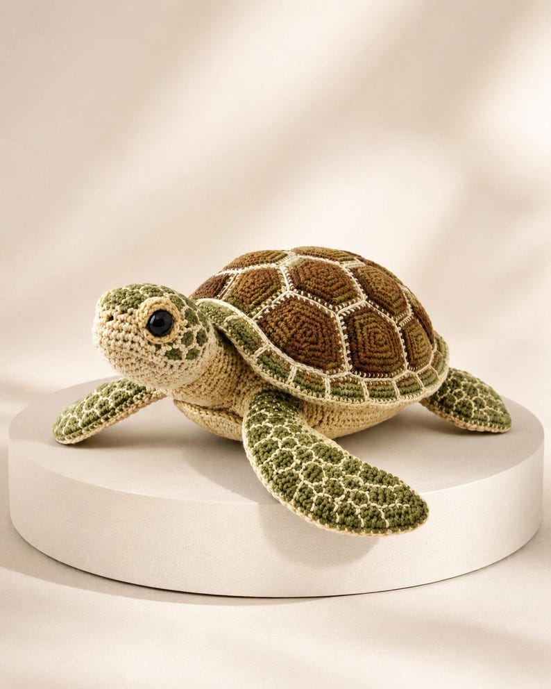 Pu&ograve; includere: Un peluche a forma di tartaruga marina realizzato all'uncinetto, con un guscio testurizzato caratterizzato da motivi geometrici marroni e verdi. La testa e le pinne sono in filato beige chiaro con accenti verdi e un occhio nero.